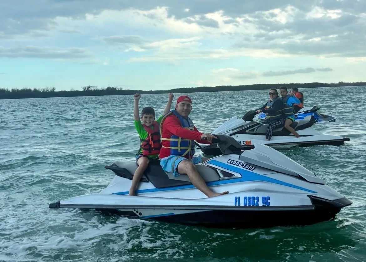 Family group including child with arms raised on jet skis in Biscayne Bay